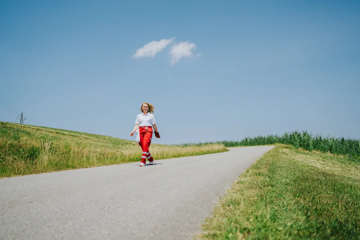 Eine Fundraiserin geht an einem Sommertag über eine Landstraße